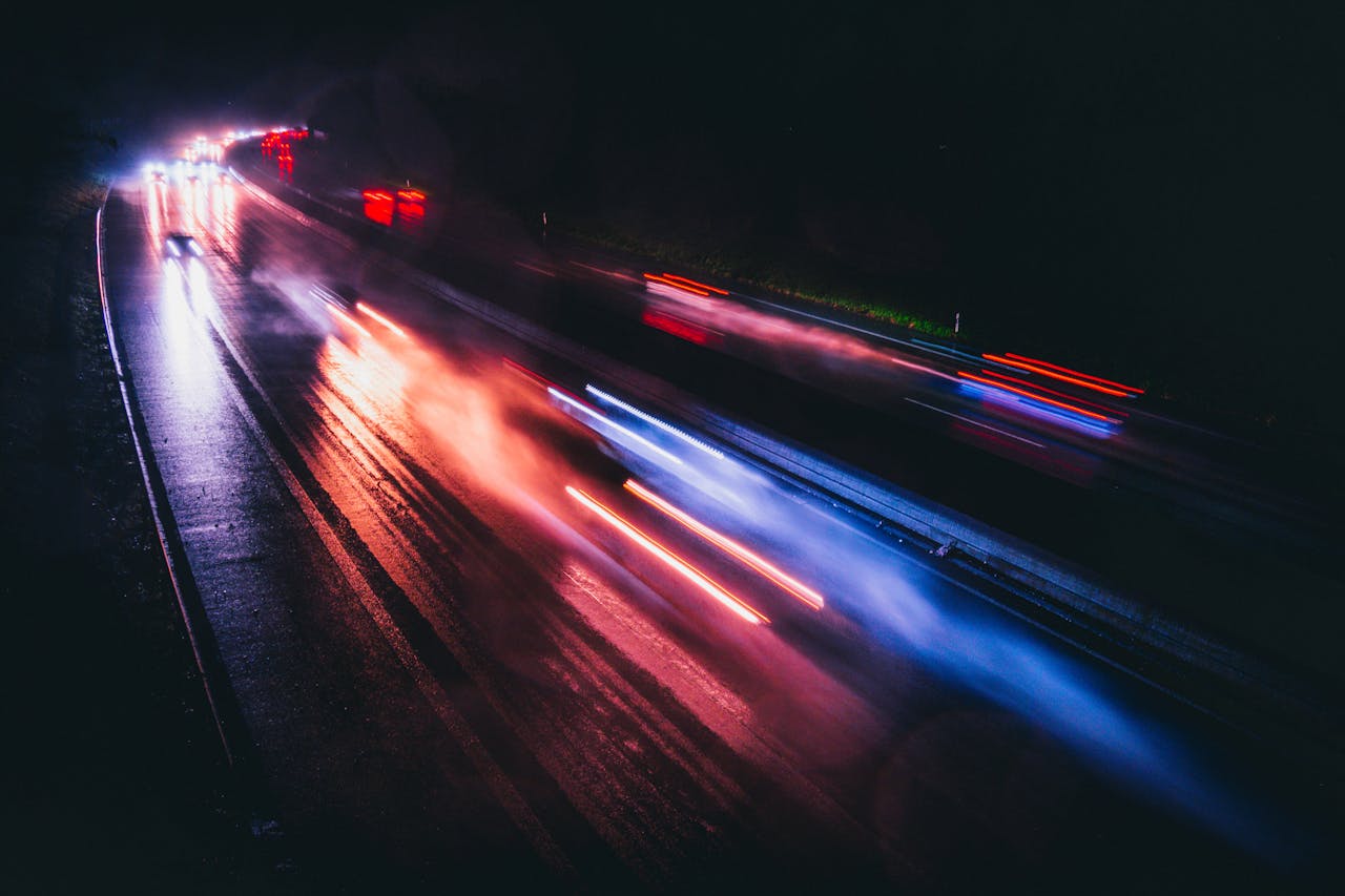 team-01 Long exposure photo capturing vibrant light trails on a rainy highway night.