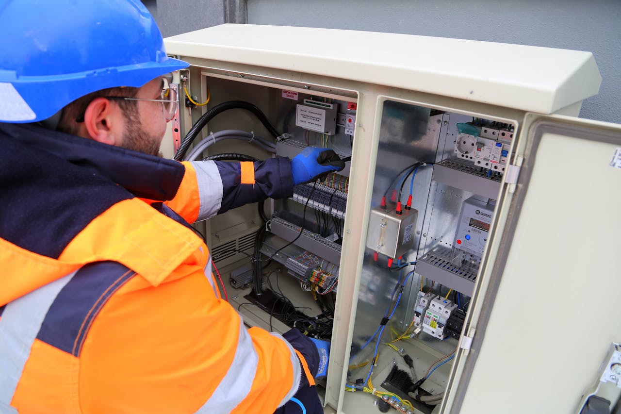services-04 Engineer in safety gear working on an outdoor electrical panel, ensuring system functionality.